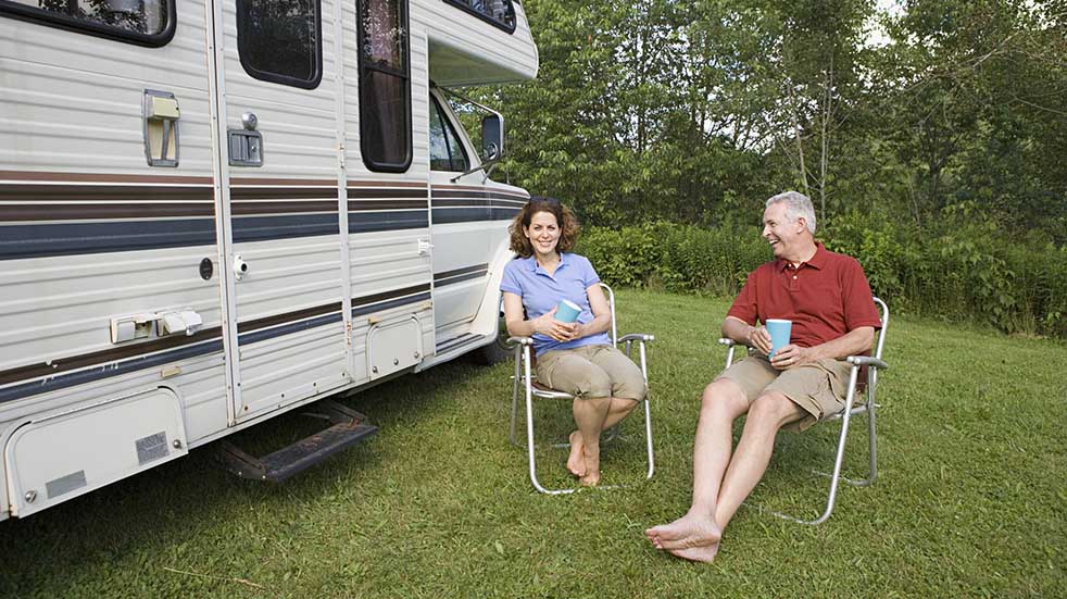 Have a safe and happy holiday couple sitting by motorhome